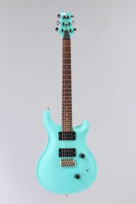 une guitare électrique bleue posée sur un support, sur fond blanc