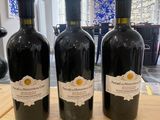 three bottles of wine sitting on top of a wooden table