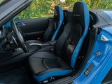 the interior of a blue sports car with black leather seats