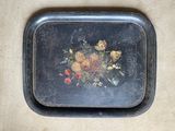 a black tray with a painting of flowers on it