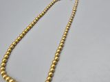 a gold beaded necklace on a white surface