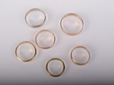 six gold wedding rings on a white background