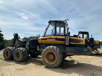 un tracteur jaune et noir garé sur la terre battue