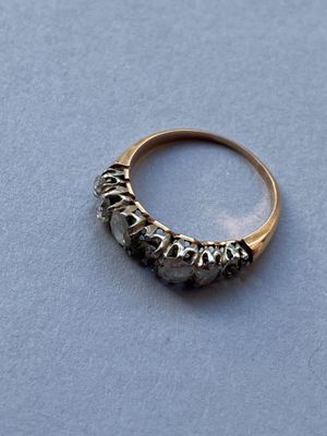 un gros plan d'une bague en or sertie de diamants noirs sur un fond bleu