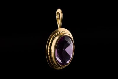 un pendentif en or orné d'une pierre d'améthorate en son centre