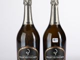 deux bouteilles de champagne posées l'une à côté de l'autre sur une surface blanche