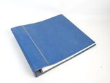 un cahier bleu posé sur une table blanche