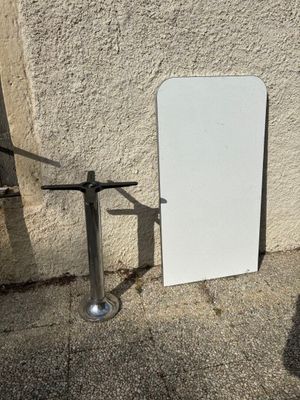 un tableau blanc appuyé contre un mur, à côté d'un poteau métallique