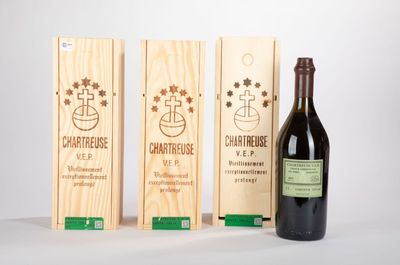 trois caisses à vin en bois et une bouteille de vin posées sur une table