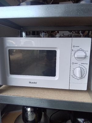 un micro-ondes blanc posé sur une étagère dans une cuisine