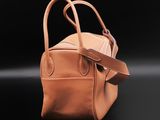 a brown leather bag with a strap on a black background