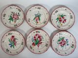six assiettes ornées de fleurs, posées sur une surface blanche