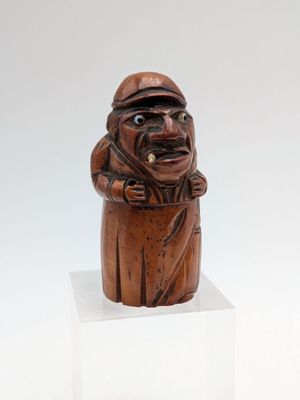 an old wooden statue of a man with a hat and a cane