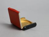 un petit étui à cigarettes rouge et doré posé sur une surface blanche