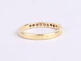 a yellow gold ring with black diamonds on a white background