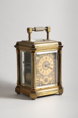 a small brass clock with a glass case on it