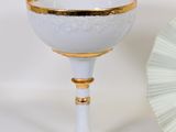 a white and gold cup and a fan on a table