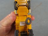 a hand holding a yellow toy truck that is sitting on a table