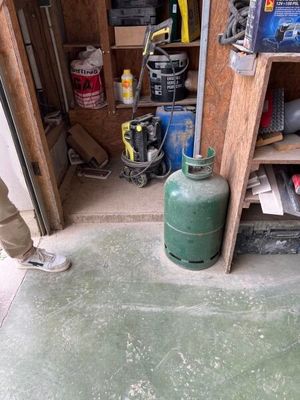 un homme debout dans un garage, tenant un bidon d'essence
