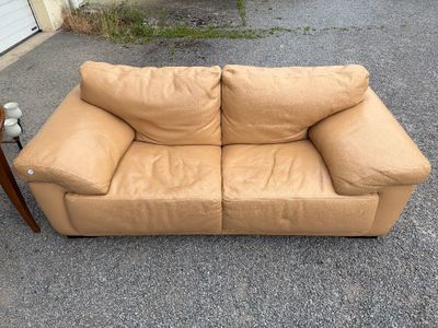 beige leather couch with wooden legs in front of a garage