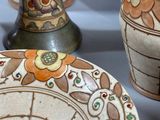 three vases and a plate sitting on a table