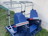 a blue cart sitting on top of a grass covered field next to a wall