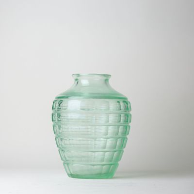 un vase en verre vert posé sur une surface blanche