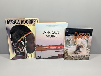 Trois livres sont posés sur une table, avec un chien devant eux.