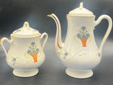 two white teapots with flowers on them on a table