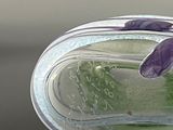 a glass vase with a purple flower inside of it