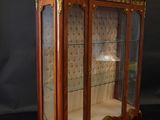 an antique wooden display case with glass doors and gold trimming