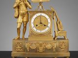 une horloge en or surmontée d'une statue représentant un homme tenant un livre