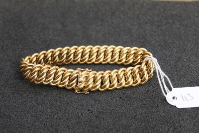 gros plan d'un bracelet en chaîne en or sur une surface noire