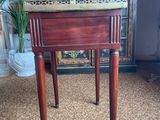 an old wooden table with a marble top and two legs