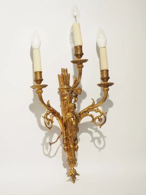 an image of a golden wall light with three candles on it