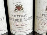 three bottles of red wine are lined up on a shelf