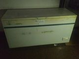 a small white refrigerator in a room with a brown floor
