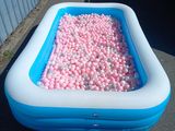 une piscine remplie de balles roses et blanches au milieu de la rue