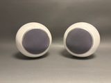 two white speakers sitting next to each other on top of a table