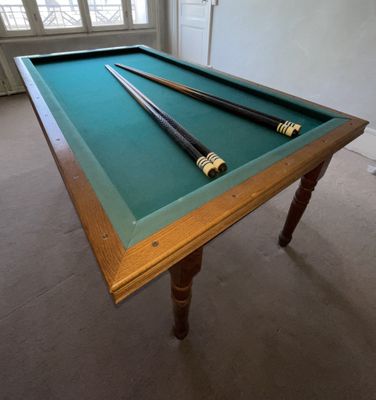 une table de billard sur laquelle sont posées deux queues