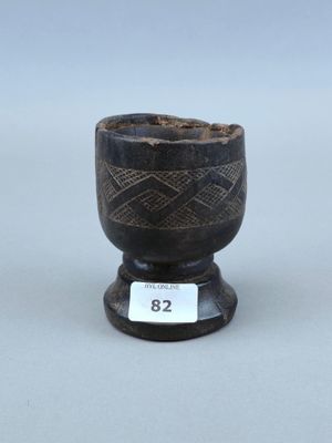 une vieille tasse en noir et blanc posée sur un socle en bois