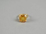 a close up of a yellow sapphire ring on a white surface
