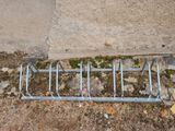 a metal bike rack on the ground next to a concrete wall