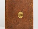 un vieux livre brun portant un emblème doré