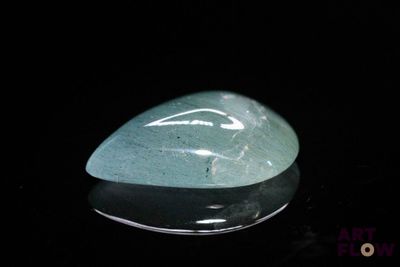 une photo d'une pierre de jade verte posée sur une surface noire