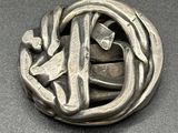 a silver brooch with a design on it on a table