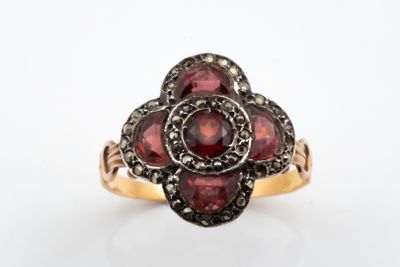 un gros plan d'une bague sertie de grenats sur fond blanc