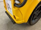 a close up of a yellow car with a sticker on it ' s bumper
