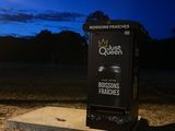 a black trash can sitting on the side of the road