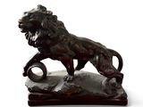 statue d'un lion perché sur un rocher, tenant une balle dans la gueule